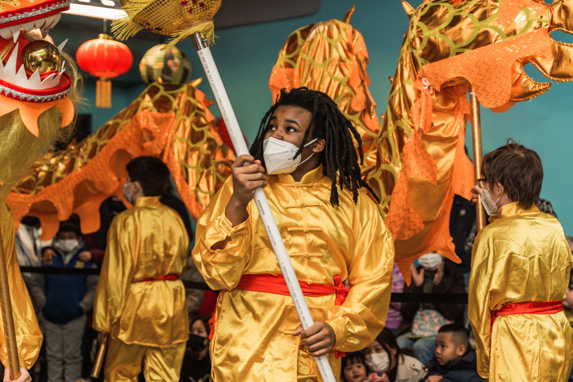 Middle school students dressed in red and gold performing the traditional Chinese Dragon Dance