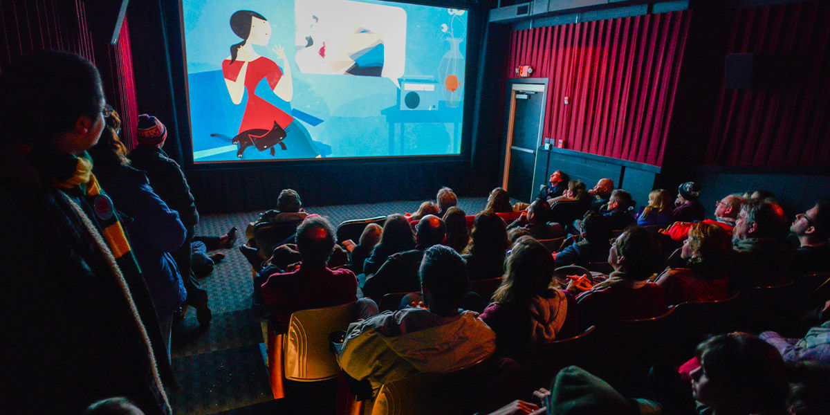 An image of a crowed movie theatre with a movie playing on screen.